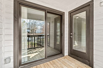 A glass door with a wooden floor and a white wall.